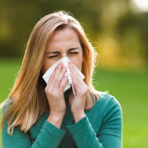 A young woman is suffering from a runny nose, one of the most common signs of seasonal allergies