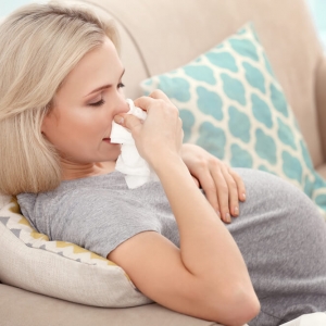 An expecting woman is struggling with allergy symptoms during pregnancy
